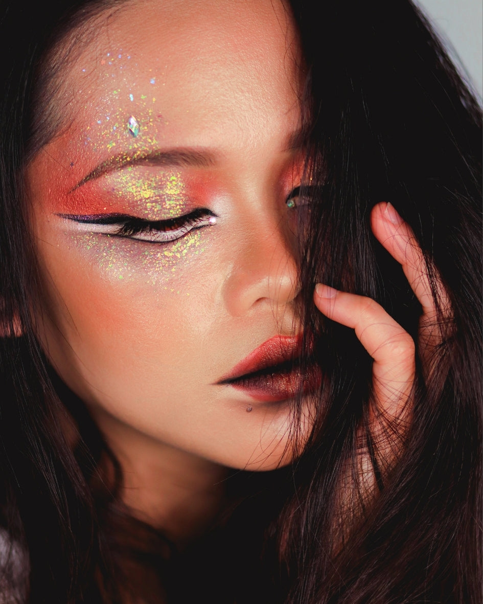 Close-up of a person with colorful makeup and glitter on their face.