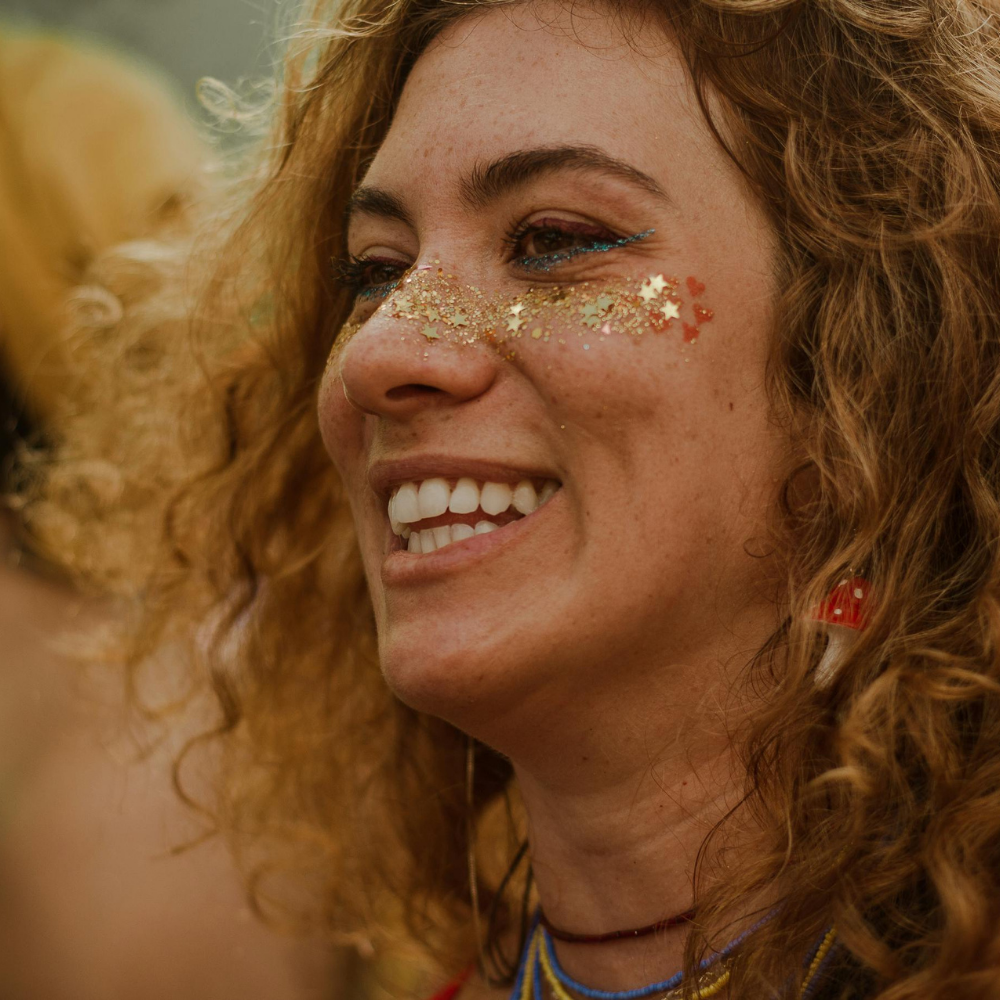 Woman with glitter on her face smiling outdoors