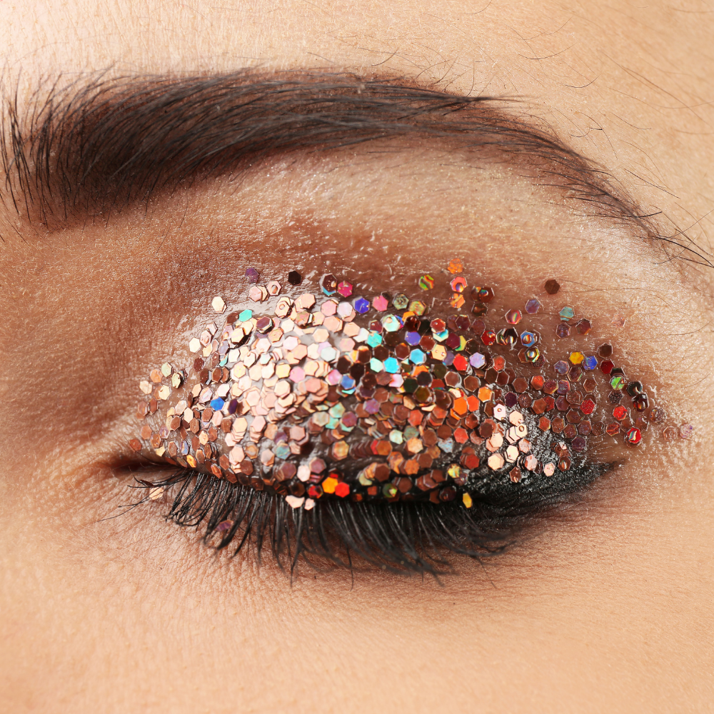 Close-up of a colorful glittery eye makeup on a person's eyelid.