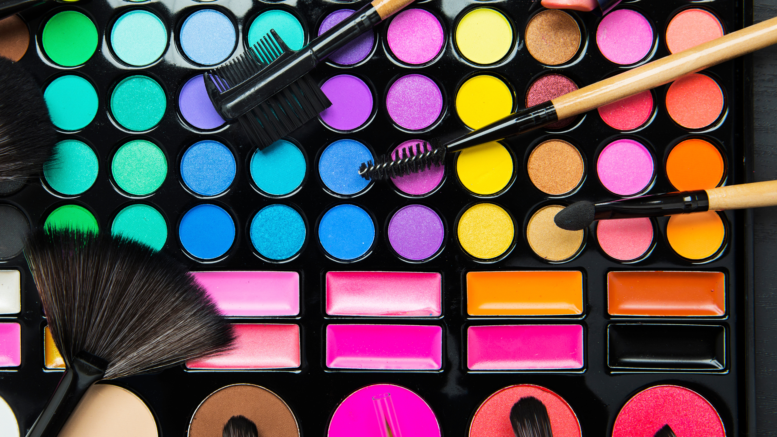 Makeup palette with colorful shades and brushes on a black background