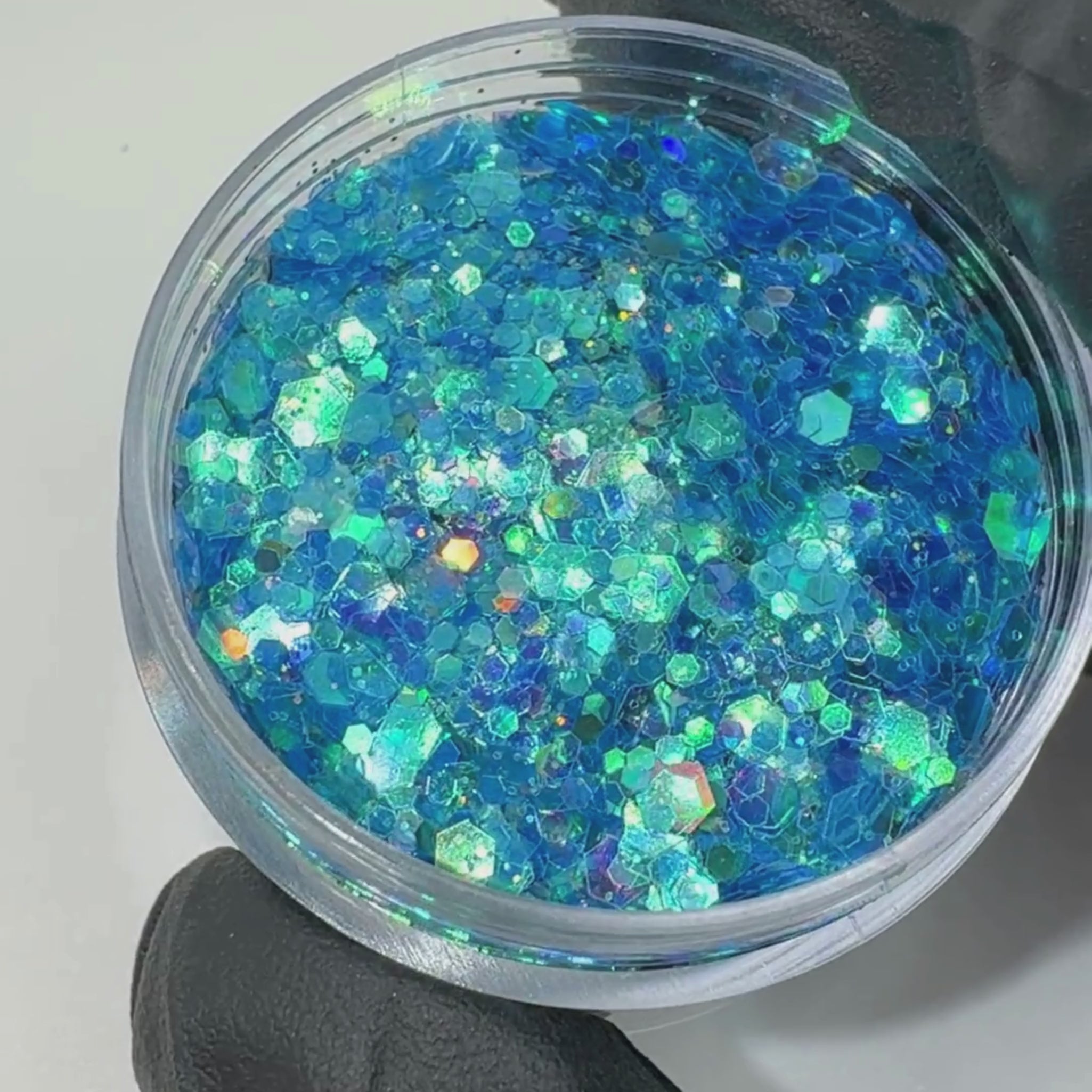 Peachipie Beauty festival glitter showcase video wth a blue iridescent chunky glitter blend in a clear plastic pot.